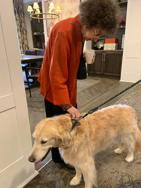 A therapy dog brings joy to memory care residents at The Neighborhood as a volunteer looks on.