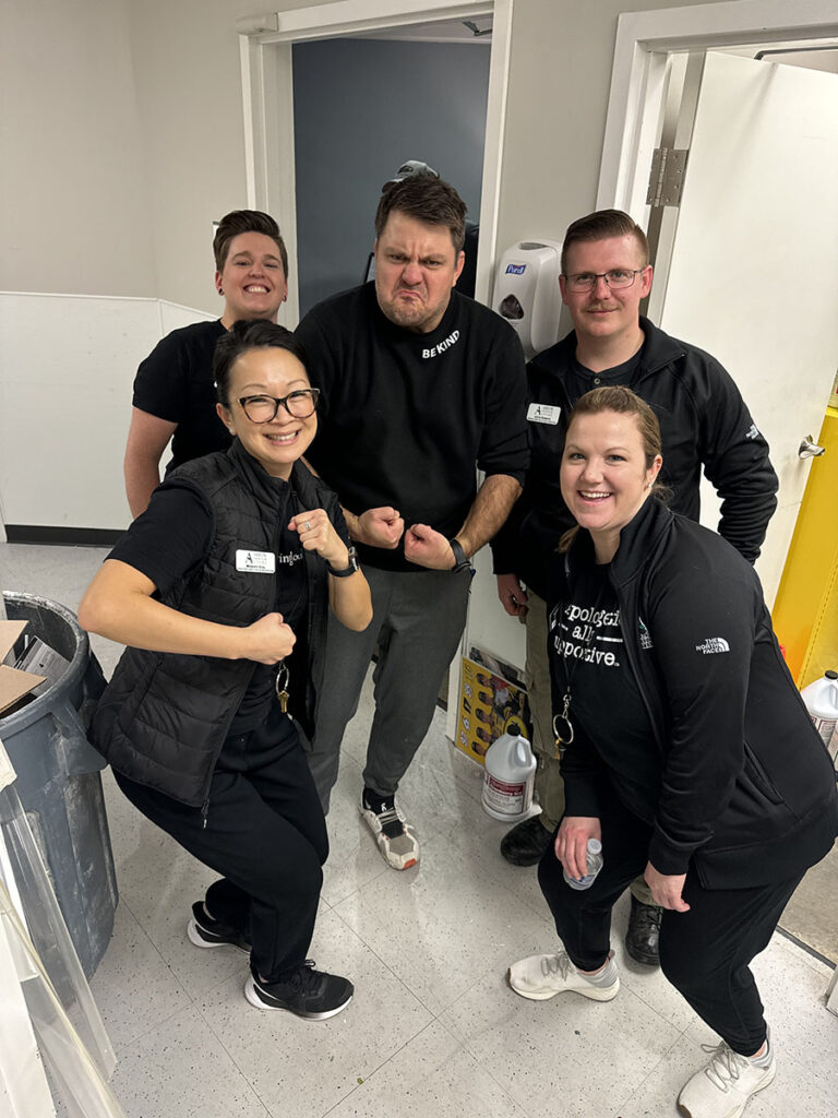 A group of employees from the company spring clean team posing for a picture in a hallway. Smiling faces and teamwork vibes!