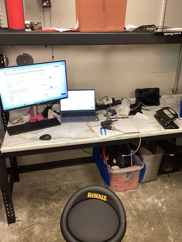 A chair and computer on a desk in a cluttered office space are being prepped for spring cleaning.