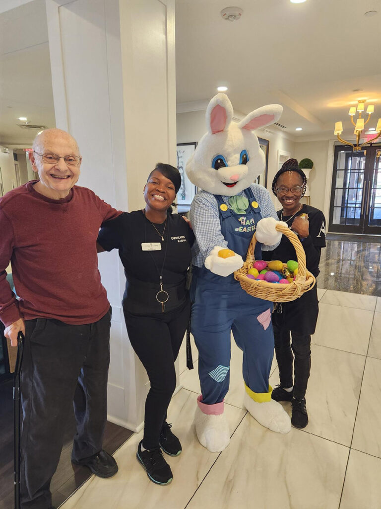 Hoppy the easter bunny smiling with elderly resident and two senior living employees at the community.