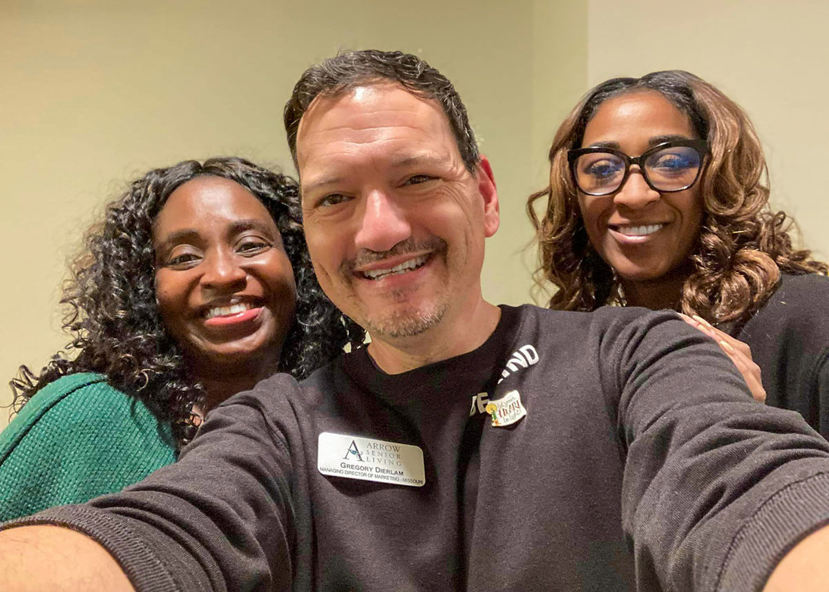 Arrow Senior Living team members pose together with smiles, showcasing teamwork and camaraderie in a positive work environment, highlighting their dedication to resident care.